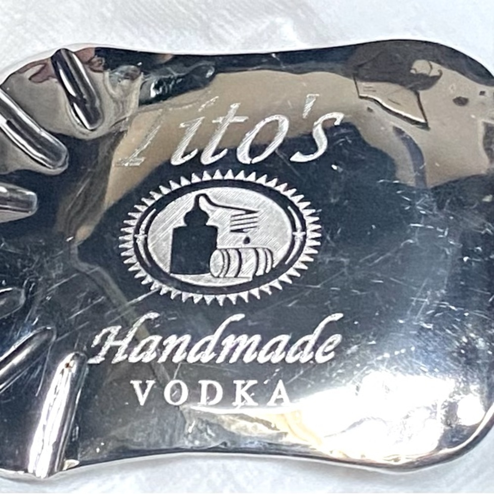Tito’s vodka belt buckle in chrome says Moody garage on the back